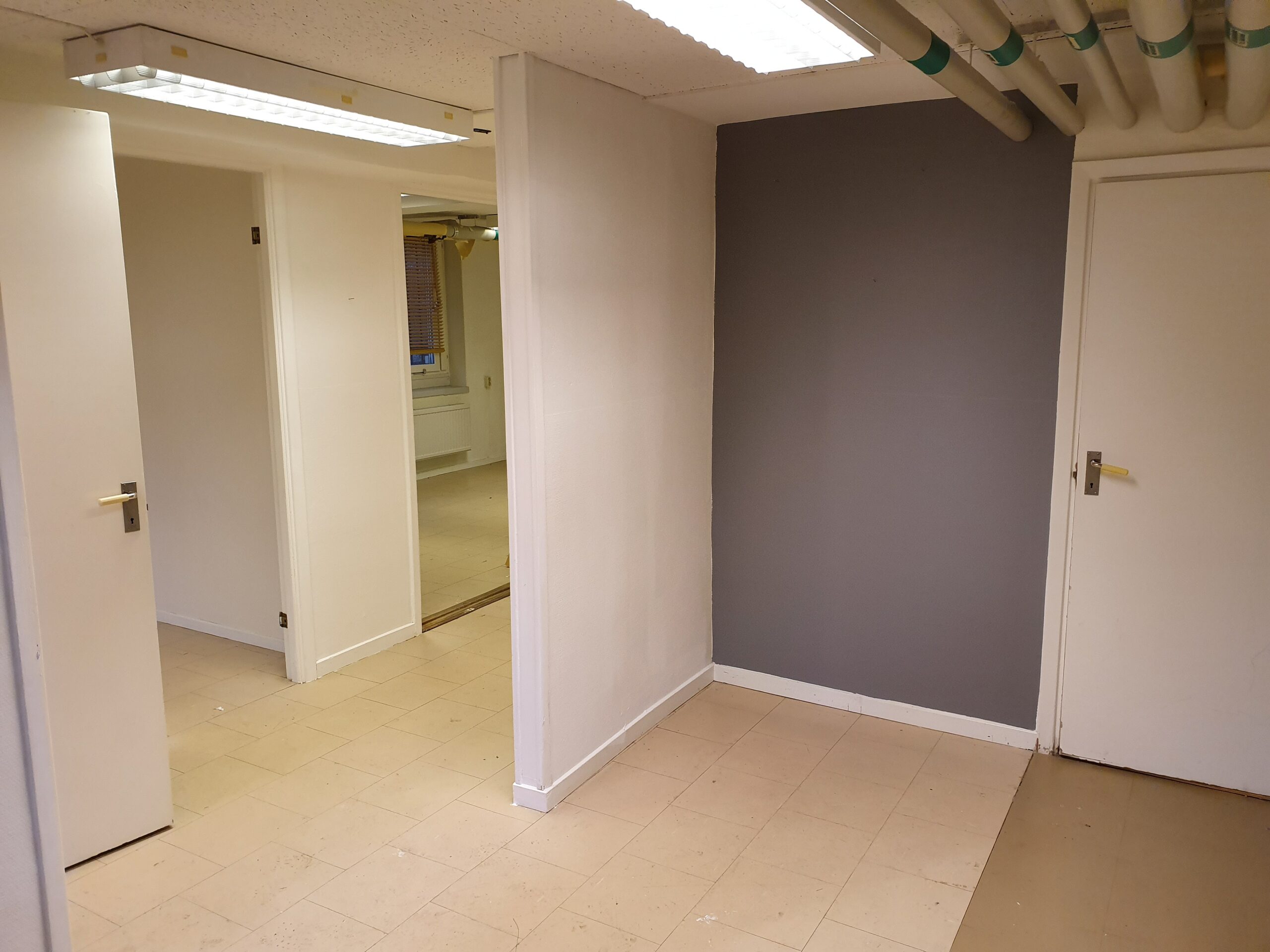 Rum med ljusa väggar samt en grå vägg och klinkegolv.