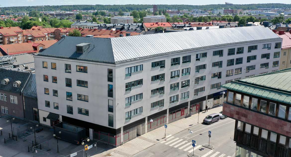 Fastighet på Drottninggatan snett från ovan, avlångt hus i fem våningar.