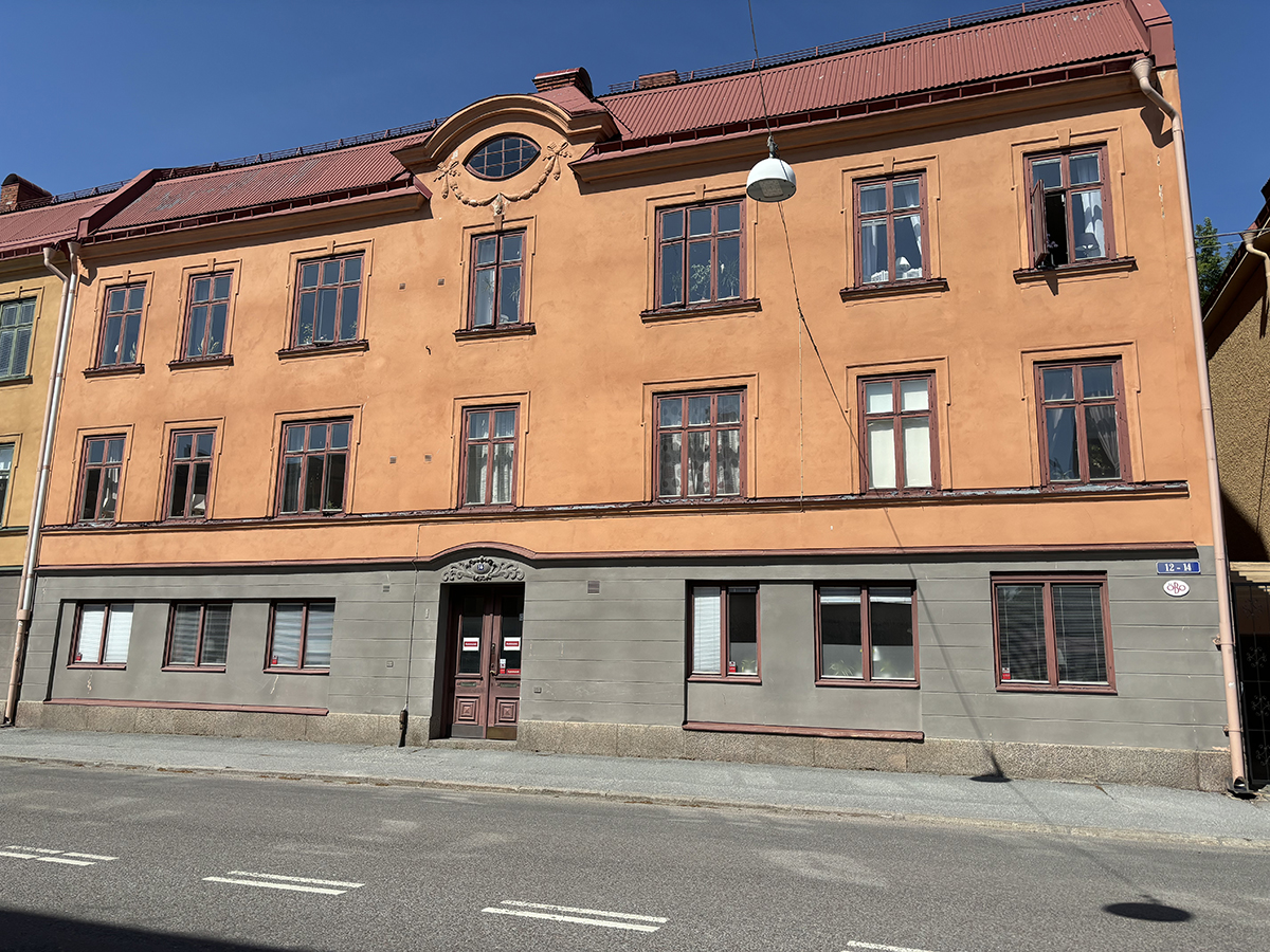 Fastighet på Karlslundsgatan, trevåningshus i äldre stil med lokaler i markplan och bostäder högre upp.