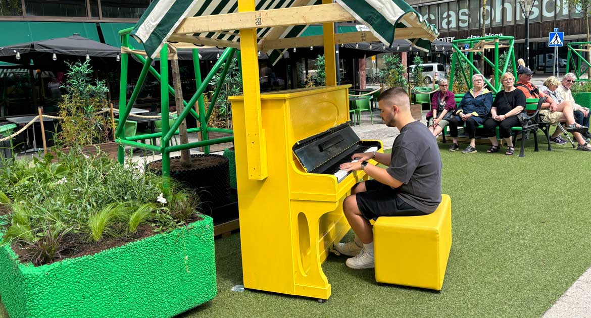 En man spelar på ett publikt gult piano på Sommartorget i Örebro.