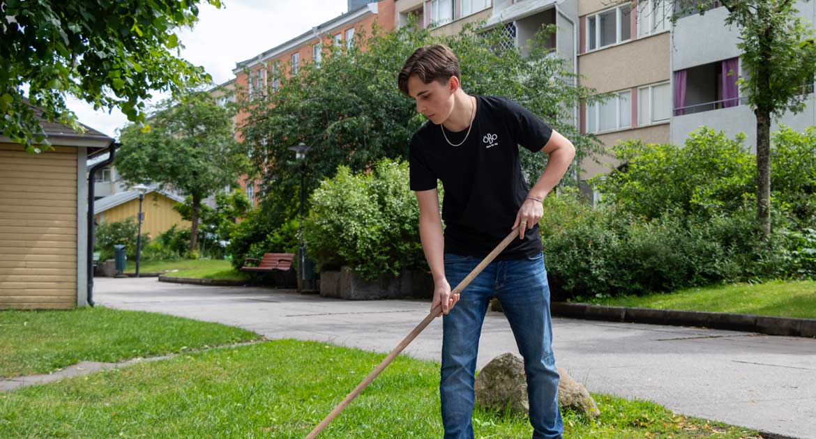 Feriepraktikanten Arvid sopar löv på en innergård på Drottninggatan i Örebro.