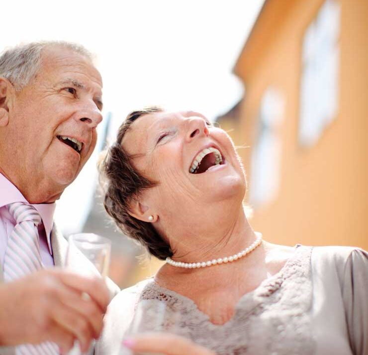 Äldre par är finklädda, skrattar och skålar.